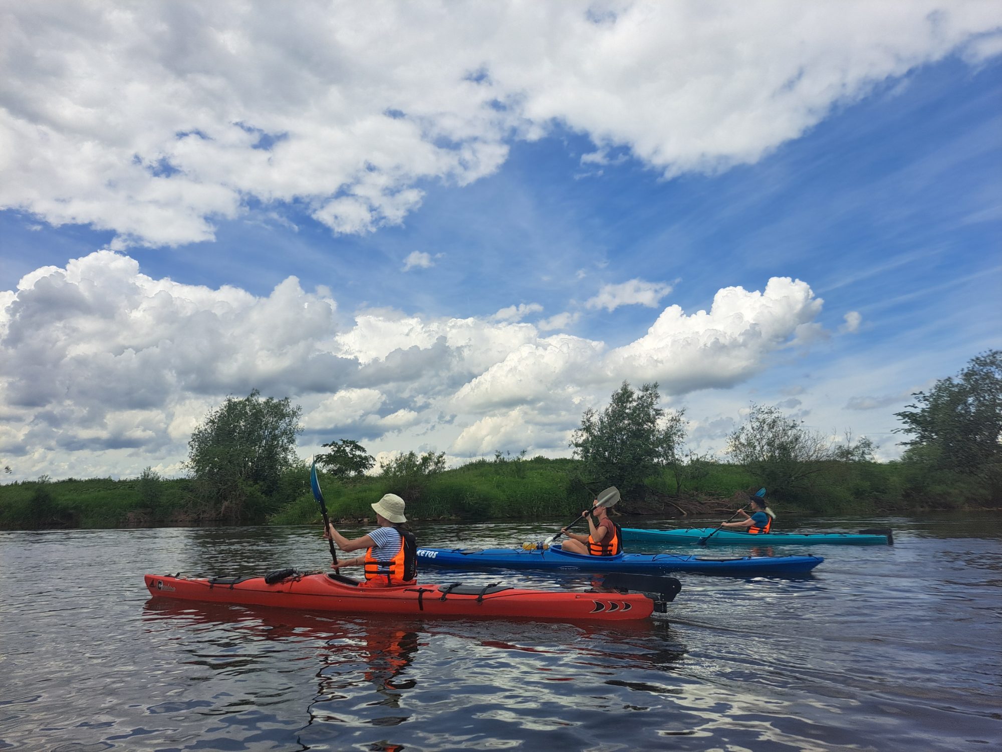 Paddlerinnen und Paddler auf der Aller unter Wolkenhimmel