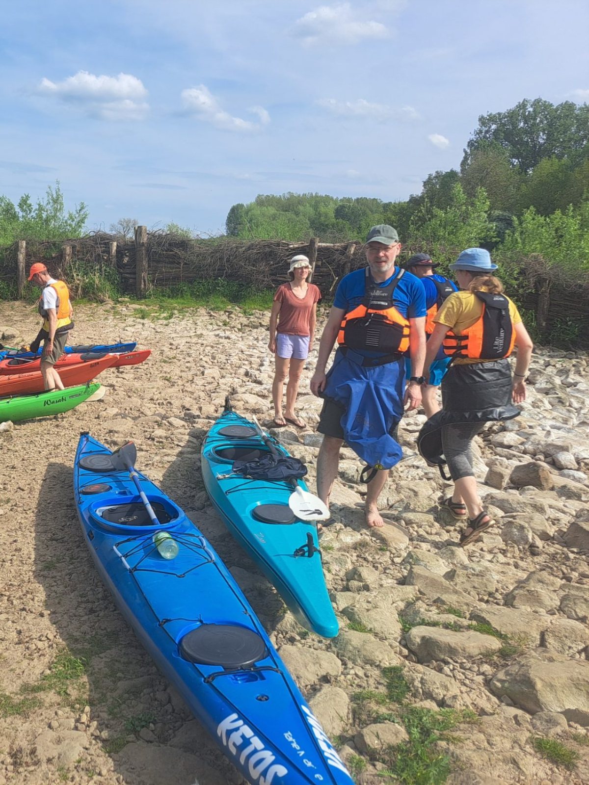 Erwachsene Paddlerinnen und Paddler mit ihren Kajaks an der Ems